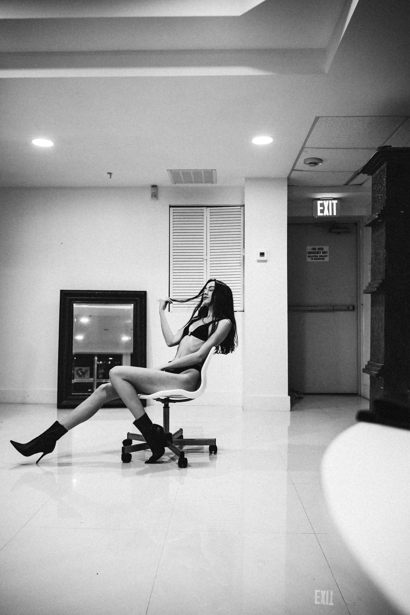 A woman in lingerie and boots sits on a chair, deciding how to turn down a phone sex request.